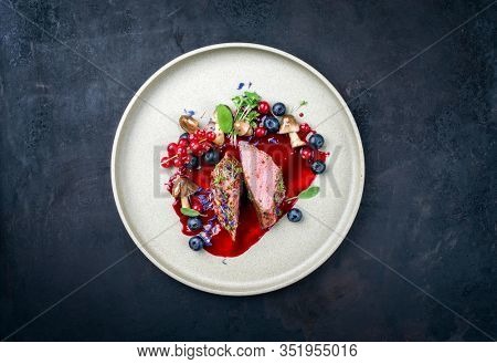 Fried dry aged venison tenderloin fillet medallion steak natural with mushrooms and forest berries as closeup on a modern design plate with copy space 