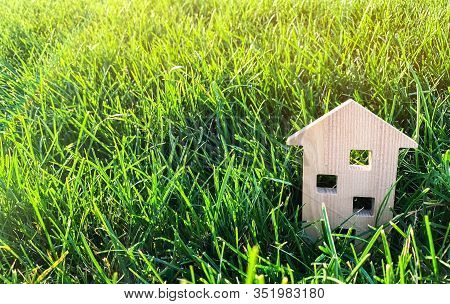 Miniature Wooden House On Green Grass. Real Estate Concept. Modern Housing. Eco-friendly And Energy 