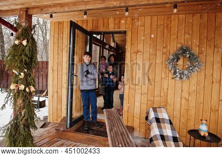 Mother And Kids In Modern Wooden House Stand Near Door Entrance.