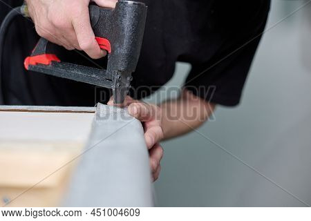Production Of Upholstered Cabinet Furniture. Worker Qualitatively Fixes The Fabric With A Pneumatic 