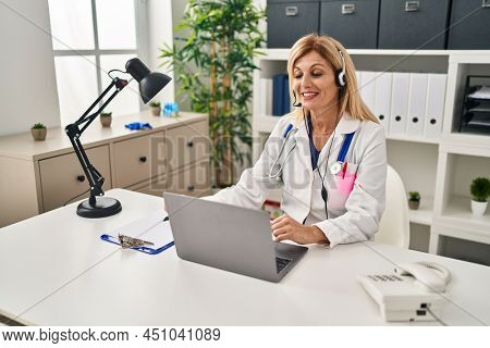 Middle age blonde woman wearing doctor uniform having medical teleconsultation at clinic