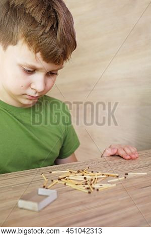 A Child Looks And Plays With Matches, A Dangerous Activity For A Toddler At Home
