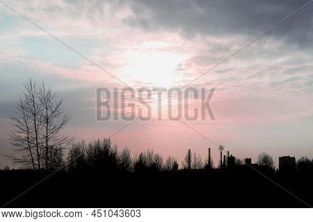 Backlit Urban View Of The City With Pipes Against The Background Of Nature