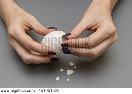 Female Hands Clean A White Boiled Egg. High Quality Photo