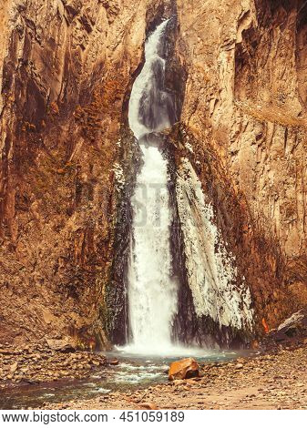 The Stream Of A Powerful Waterfall Flows Down Between The Rocks Into A Mountain River. Fullscreen Ph