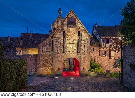 Riquewihr Village, Alsace, France. View Of Illuminated Medieval Gate Tower At Dusk