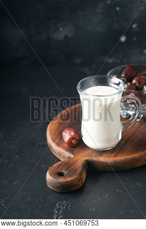 Ramadan Kareem Food And Drinks. Plate Of Dates, Glass Of Milk And Date Palm Branch On Black Backgrou