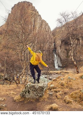 A Faceless Woman Stands In A Pose On A Stone Among Bare Birches Against The Backdrop Of Steep Cliffs