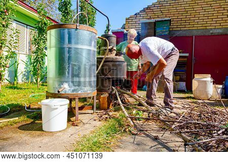 Woman Is Manually Turning Lever To Mix Fruit Marc In Boiler Of Homemade Distillery Made Of Copper, M