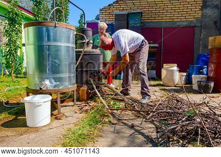 Woman Is Manually Turning Lever To Mix Fruit Marc In Boiler Of Homemade Distillery Made Of Copper, M