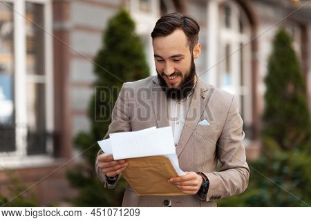 Positive Notice Of A Successful Trial By Mail. Happy Man With A Letter In His Hands Outdoors.
