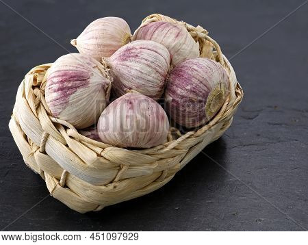 Solo Garlic, Allium Sativum In Straw Basket Isolated On Black Slate Plate Background