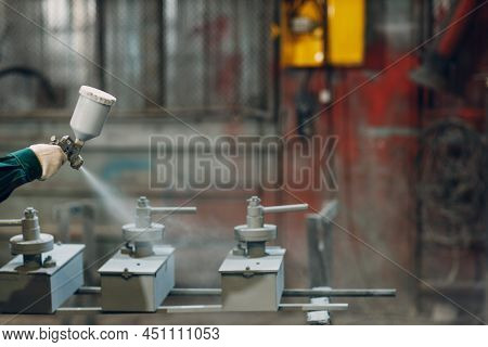 Powder Paint Coating Of Metal Parts. Worker Man In A Protective Suit Sprays Powder Paint From Gun On