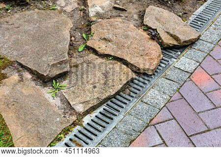 Iron Grating Of The Drainage System Near Pedestrian Sidewalk Made Of Stone Brick Tiles Landscaping W