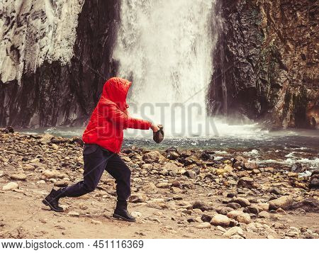 A Woman In A Red Jacket Stands Against The Backdrop Of A Stormy Waterfall Flowing Down From Wet Icy 
