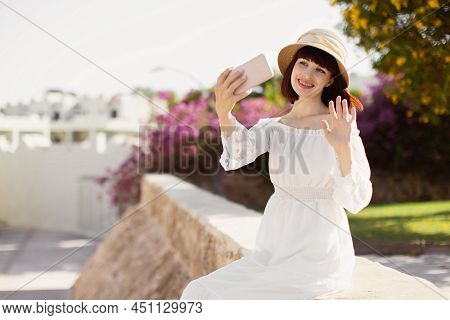 A Woman In Srtaw Hat And White Dress Using Smart Phone Or Taking A Selfie On The Tropical City In Su
