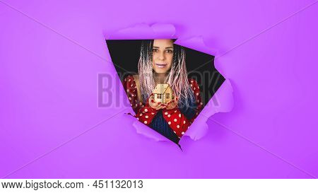 Woman With Toy House Looking Through Hole In Paper. Female With Afro Braids And Miniature Wooden Hou
