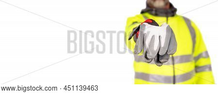 A Construction Worker In A Bright Yellow Hi-viz Coat Giving White  Safety Gloves To The Viewers Isol