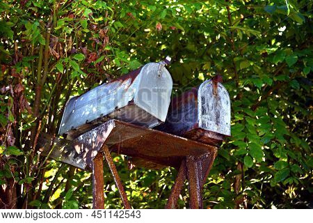Two Mailboxes Are Weathered, Rusty And Derelict.  They Cling To A Leaning, Rusty, Metal Support.
