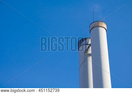 Chimneys Of A Wood Pellet Power Plant For Local Heating Supply In Front Of Blue Sky