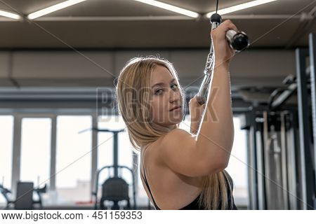 Young Beautiful Blonde Woman Trains In The Gym. Pulldown Exercise. Back Muscle Training