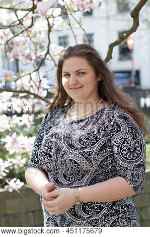 Portrait Of A Beautiful Plump Caucasian Confident Woman In Magnolia Flowers