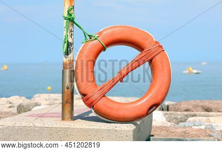 Orange Plastic Lifebelt In The Seashore Without People