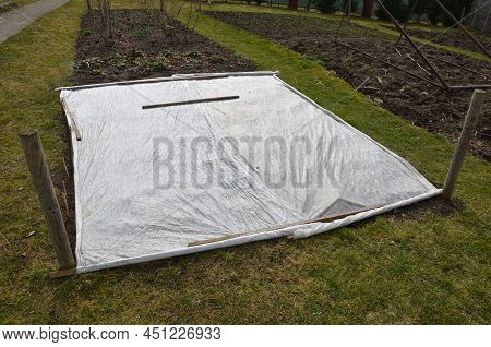 Frost Protection Of Vegetables. The Gardener Covered The White Breathable Foil Bed. Frost Does Not B
