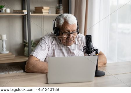 Older Man Wear Headset Look At Laptop Speaking Into Microphone