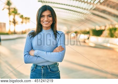 Beautiful hispanic woman smiling confient with crossed arms at the city