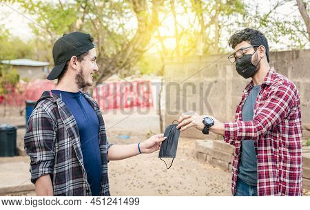 Two Young People Giving Each Other A Mask, Image Of A Young Man Giving A Mask To Another Person, Con