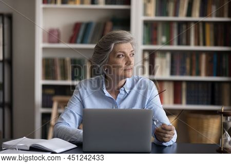 Older Businesswoman Sit At Workplace Distracted From Work Staring Aside