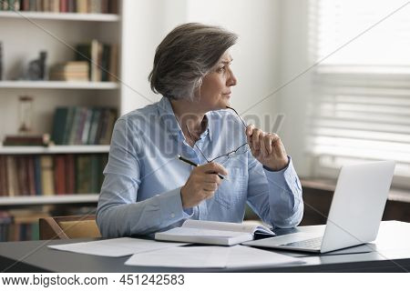 Thoughtful Middle-aged Businesswoman Takes Off Glasses Staring Out Window