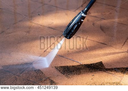 Cleaning Dirty Backyard Paving Tiles With Pressure Washer Cleaner.