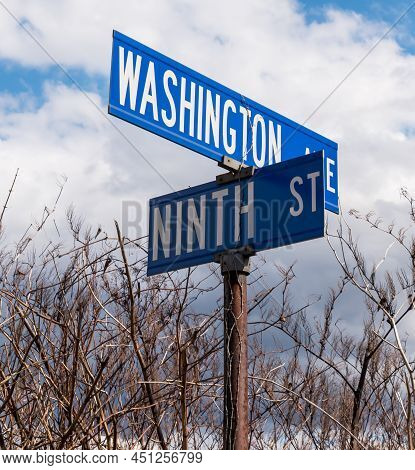 Street Signs In Braddock, Pennsylvania, Usa Under Beautiful Skies And Bare Trees In The Background