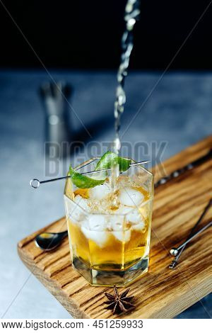 Alcohol Fresh Rum Cocktail Pouring From Shaker Into Gless With Lime Peel Ice On Wooden Desk At Black