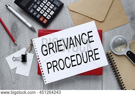 Grievance Procedure Text On Open Notepad On Red Notepad