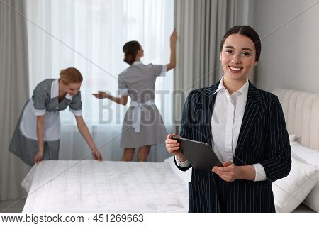 Housekeeping Manager With Tablet Checking Maid's Work In Hotel Bedroom