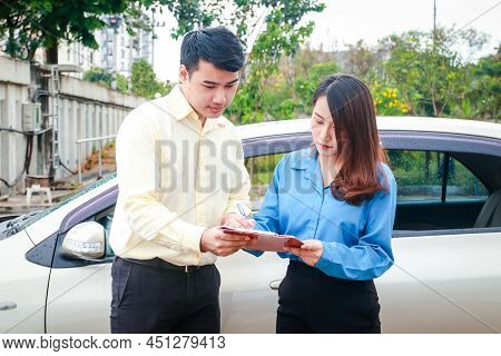 Woman Signing Paperwork To Claim Car Insurance With Insurance Company Employee Because She Was Drivi