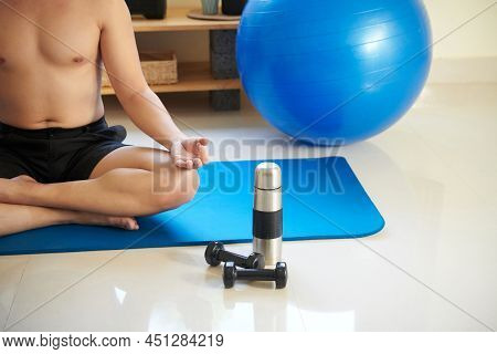 Themos And Dumbbells On The Floor Next To Fit Young Man Meditating In Lotus Position