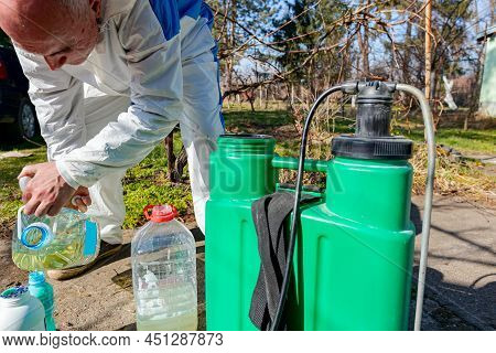Farmer Is Preparing Mixture Of Water And Botanical Solutions Of Pesticide In Plastic Knapsack Spraye
