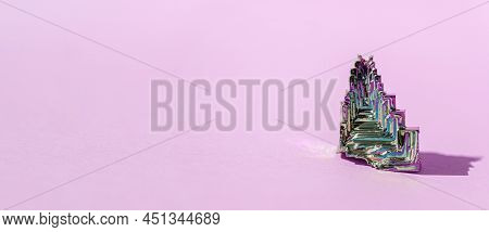Synthetic Bismuth Bismuthum Crystal With Iridescent Oxide Film On Pink Background Close Up Isolated.