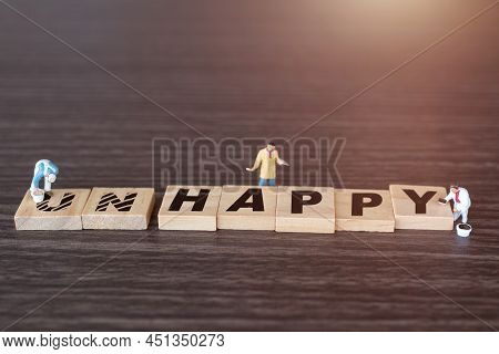Worker Team On Unhappy Word In Wooden Alphabet Letters With Prefix Un Crossed Out, Leaving The Word 