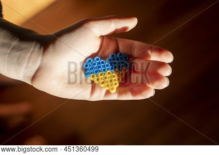 Small Children's Hand Holds In The Palm Of The Hand The Flag Of Ukraine In The Form Of A Heart In A 