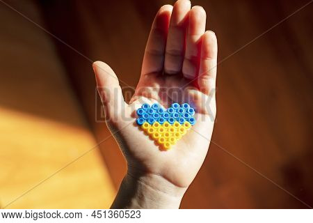 Small Children's Hand Holds In The Palm Of The Hand The Flag Of Ukraine In The Form Of A Heart In A 