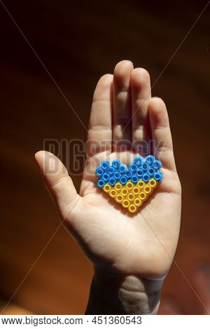 Small Children's Hand Holds In The Palm Of The Hand The Flag Of Ukraine In The Form Of A Heart In A 
