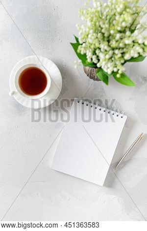 Bouquet Of Flowers Lily Of The Valley In A Vase, Coffee Cup And Notebook On White Background. Copy S