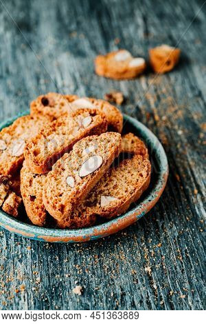 some spanish carquinyolis, almond biscuits typical of catalonia, similar to italian biscotti, in a rustic green ceramic plate, on a gray rustic wooden table