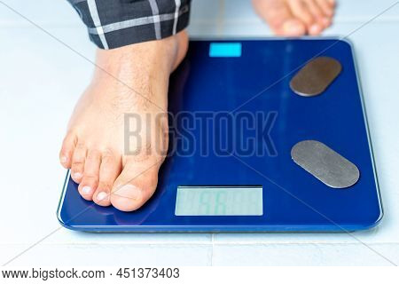 Close Up Of A Mans Feet As He First Places One Foot On The Weight Scale To Start The Measurement. Ch