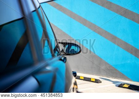 Side View Of A Mirror On A New Black Car.